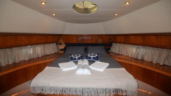 The bedroom on the motor yacht Act features a large and comfortable bed, nautical decor, and lighting.